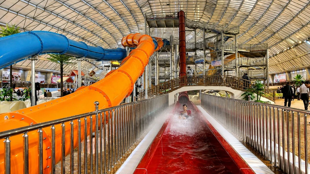 The blue and orange flume tubes of the Abotab water park, with a rider splashing down a straight run-out chute