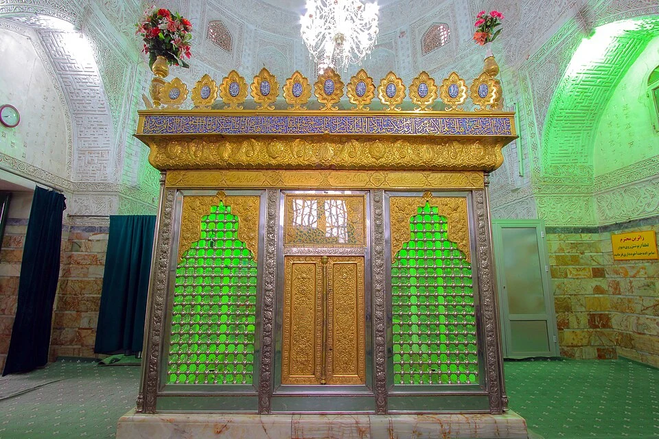 The gold and silver zarih over the grave of Ahmed bin Qasim inside his shrine in Qum, its green lattice panels lit beneath a decorated vault