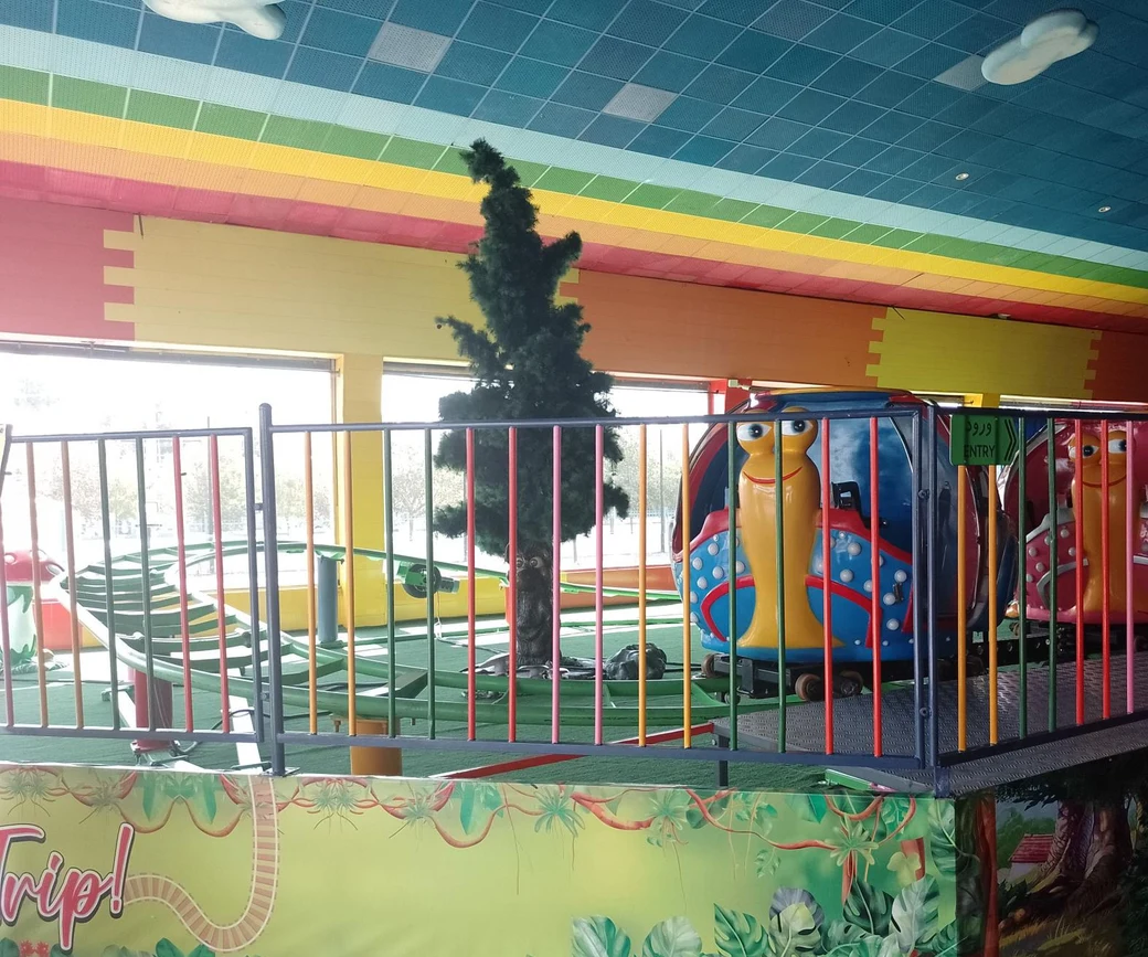 A children's mini-train on its track beneath a rainbow-striped ceiling at the Rangeen Koman indoor park
