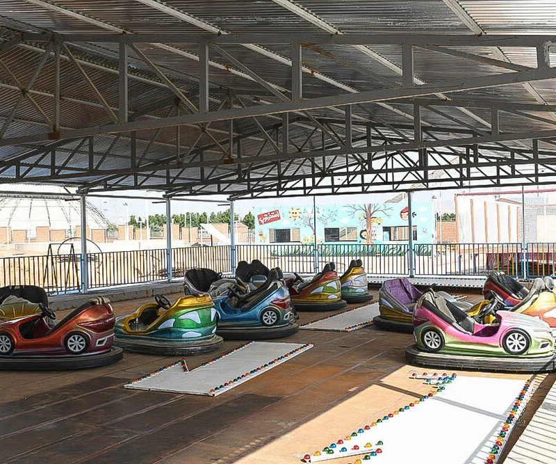 Rows of brightly painted bumper cars parked on the rink under a steel canopy