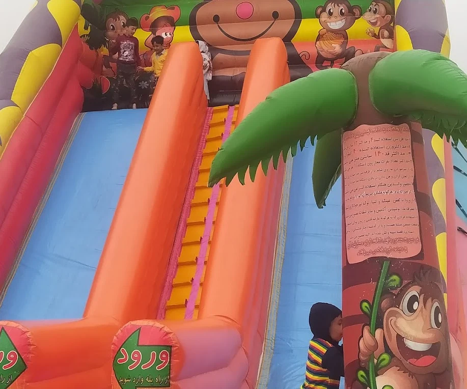 Children climbing a large inflatable slide decorated with monkeys and palm trees at Ghadeer Park