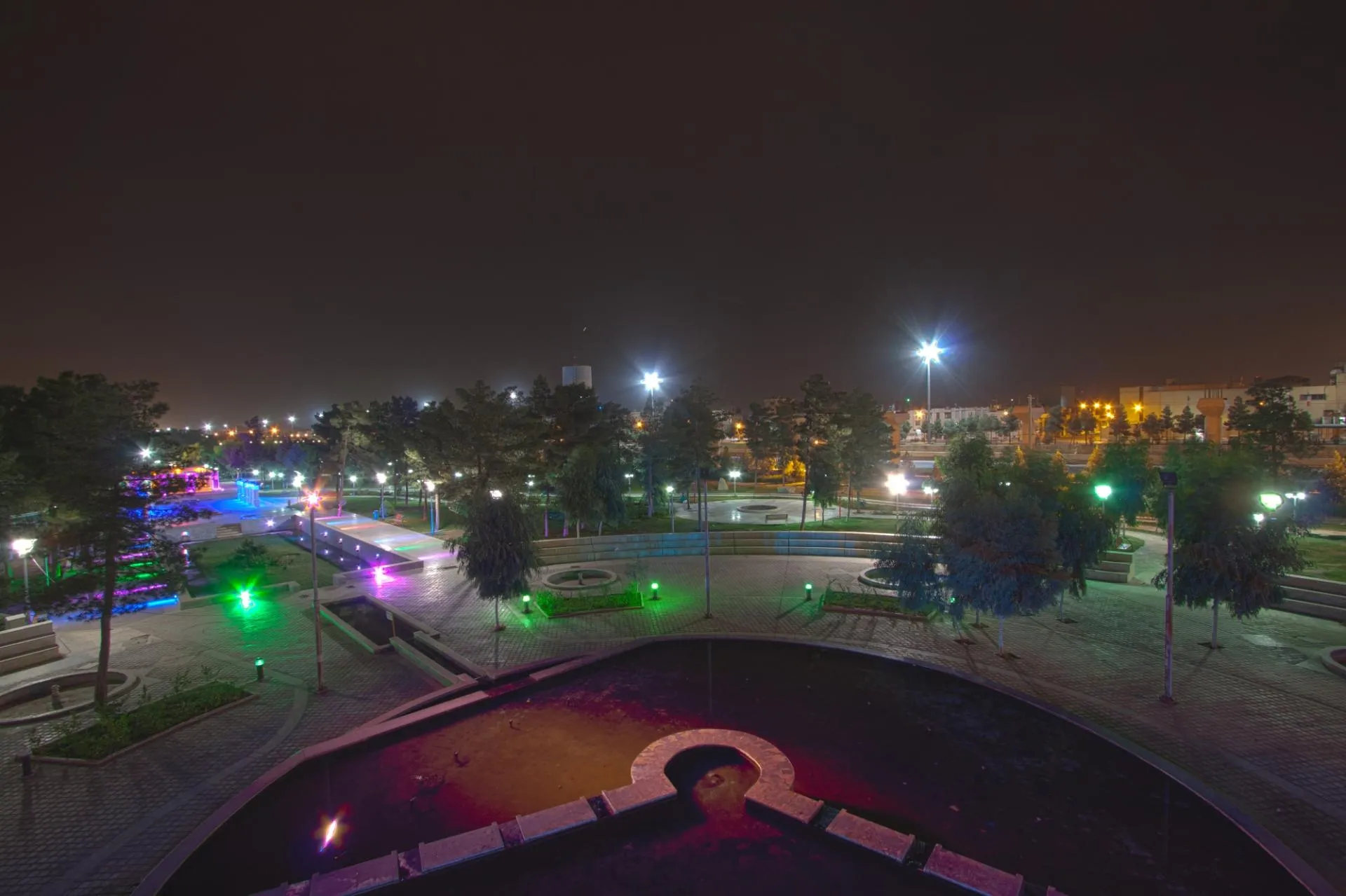 Bonyadi Park at night, its walkways, fountains and lawns lit up with colourful green, pink and blue lighting
