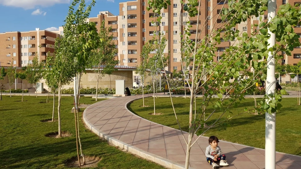 A landscaped walkway winding through the greenery and playground at Koodak Park