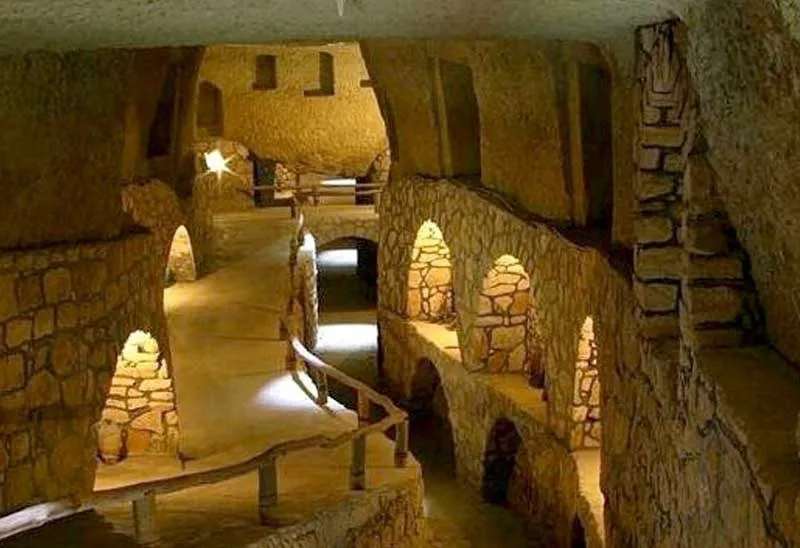 The stone tunnels and chambers of the underground city of Nushabad near Kashan, with arched passageways and small alcoves lit by warm lamps