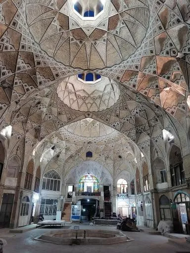 Interior of a historic Qum bazaar with an intricately tiled vaulted brick dome and skylights above the alleyways
