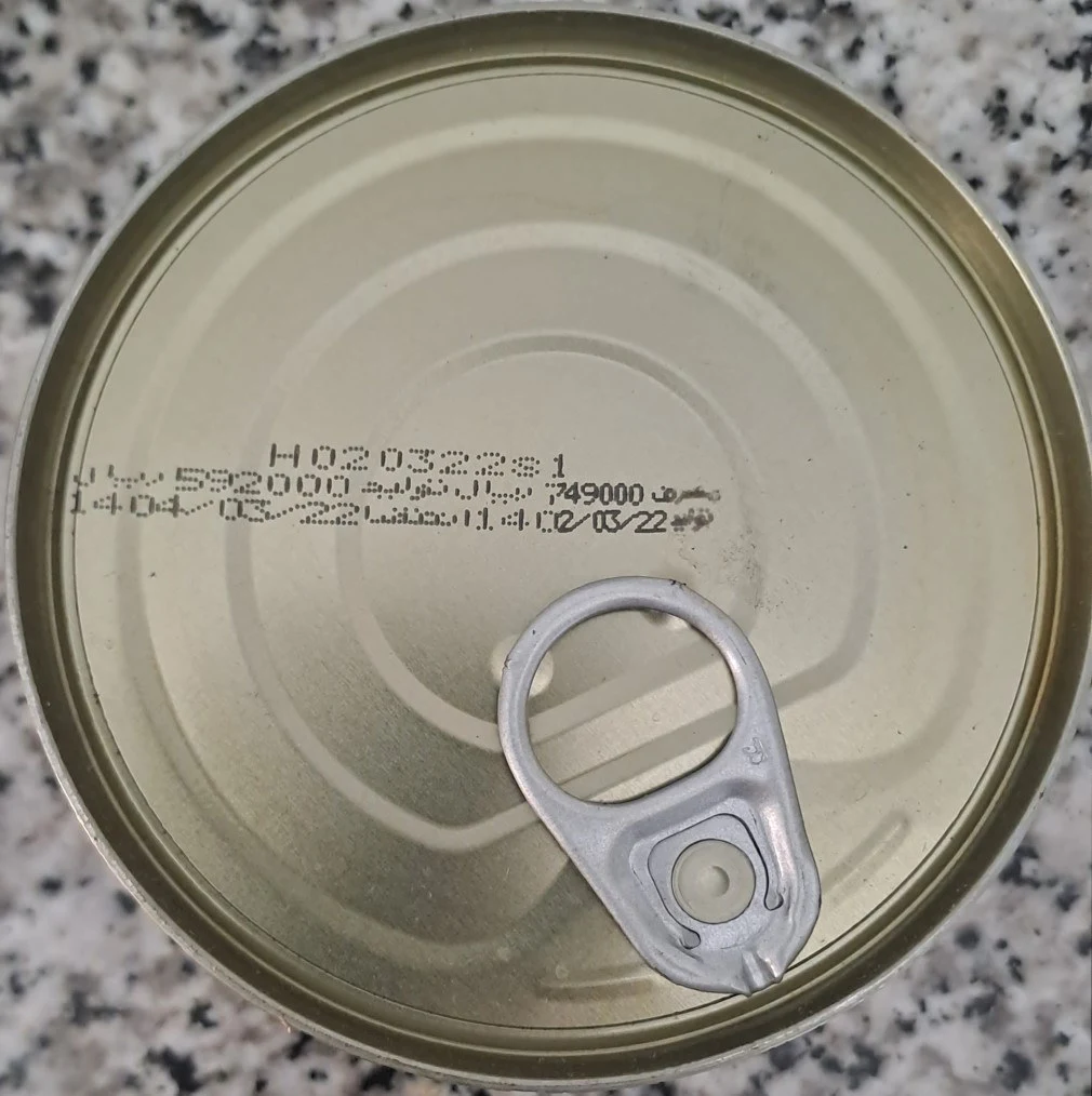 The lid of a canned food product stamped with its batch number, production and expiry dates and price