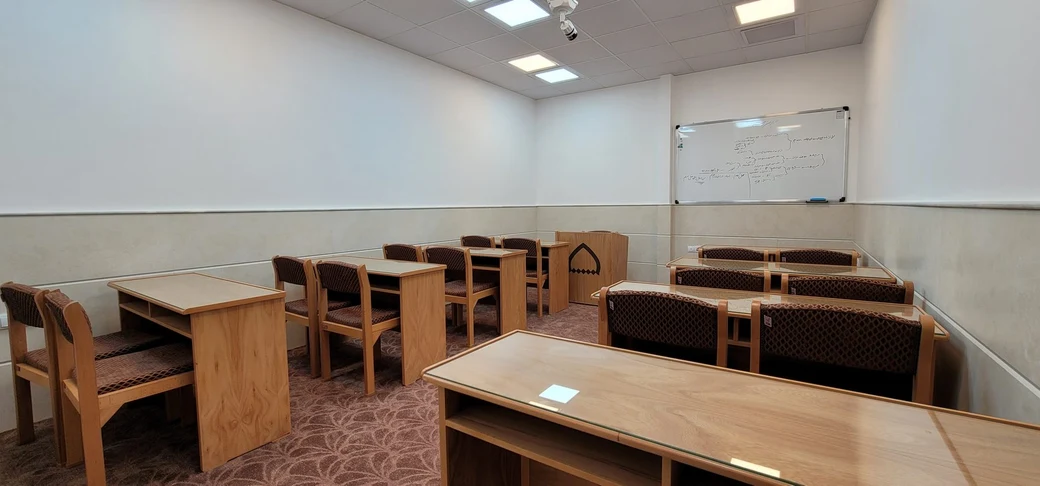A modern SIOS classroom with rows of light-wood study desks and chairs facing a whiteboard