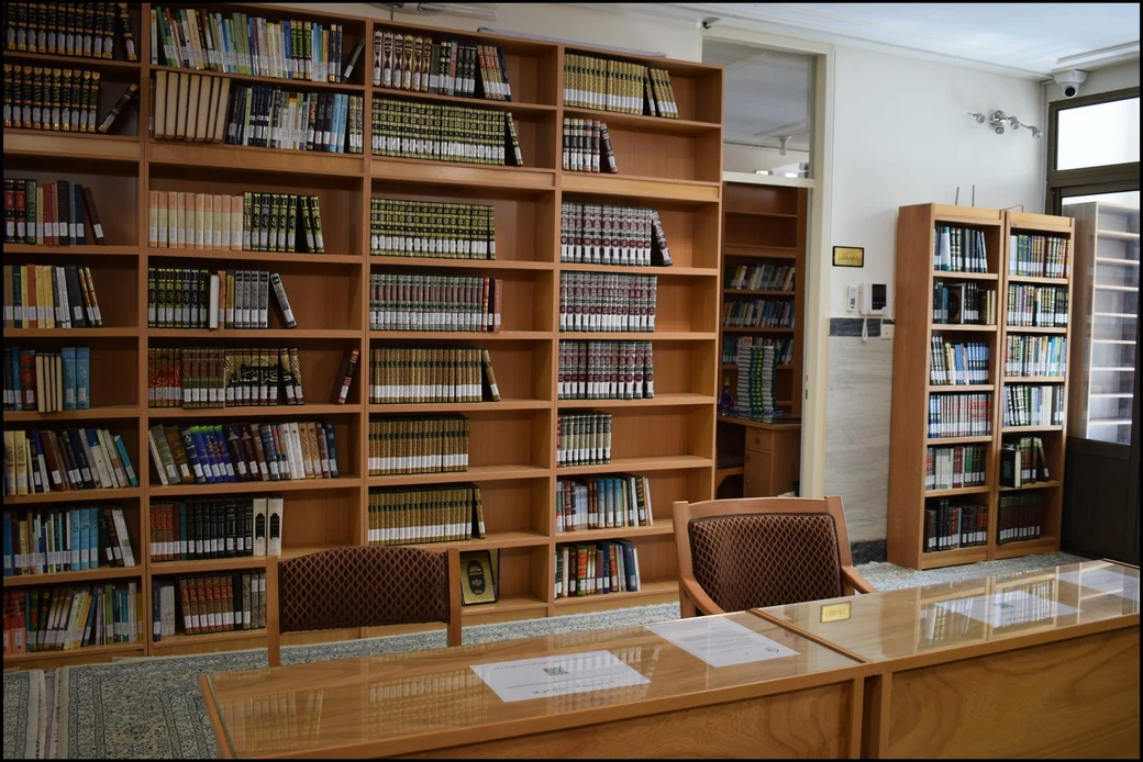 Another view of the SIOS library, showing tall bookcases packed with bound volumes and a glass-topped reading desk