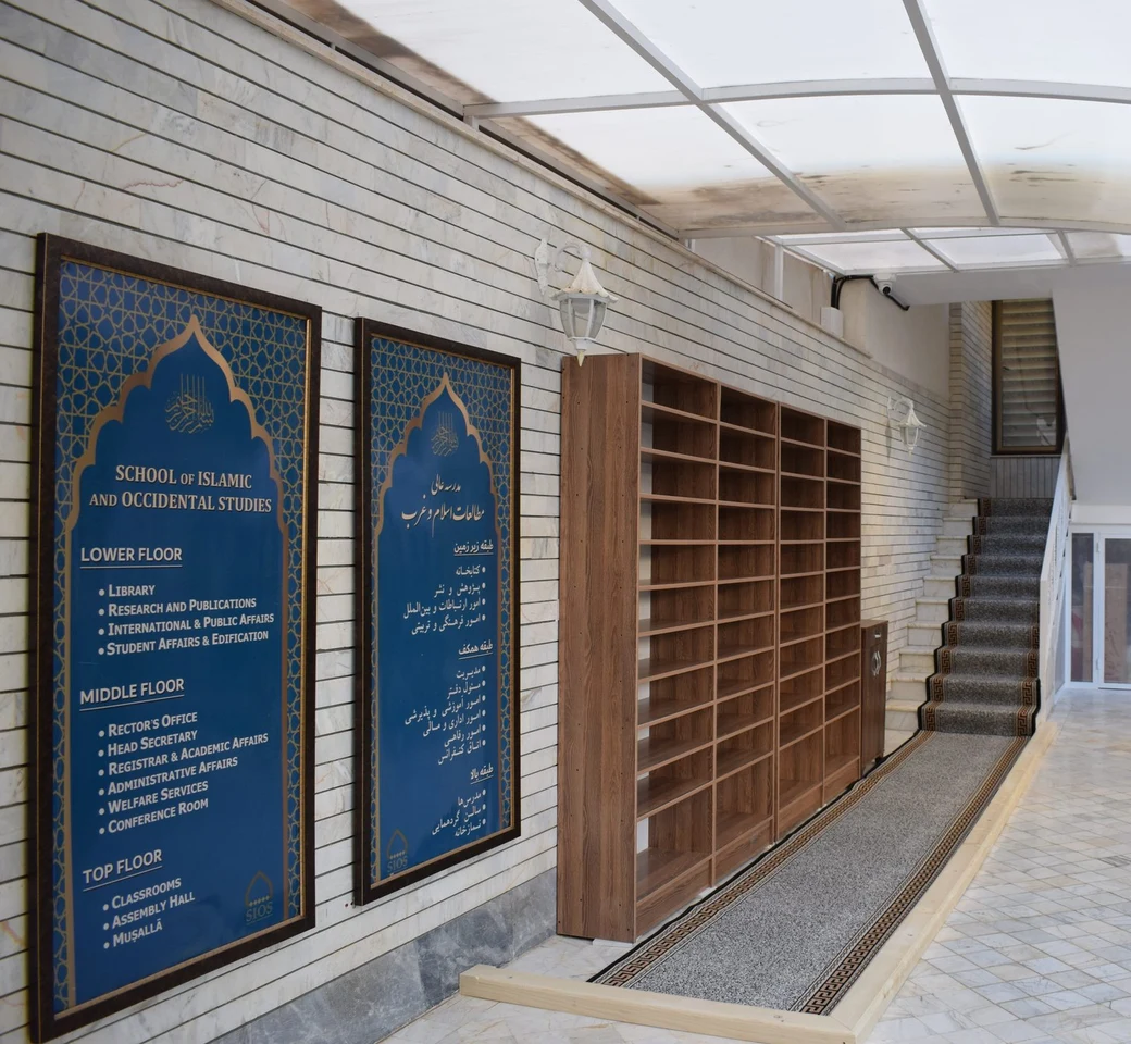 A blue floor-directory sign in a SIOS corridor, reading 'School of Islamic and Occidental Studies' in English beside its Persian equivalent, listing the departments on the lower, middle and top floors